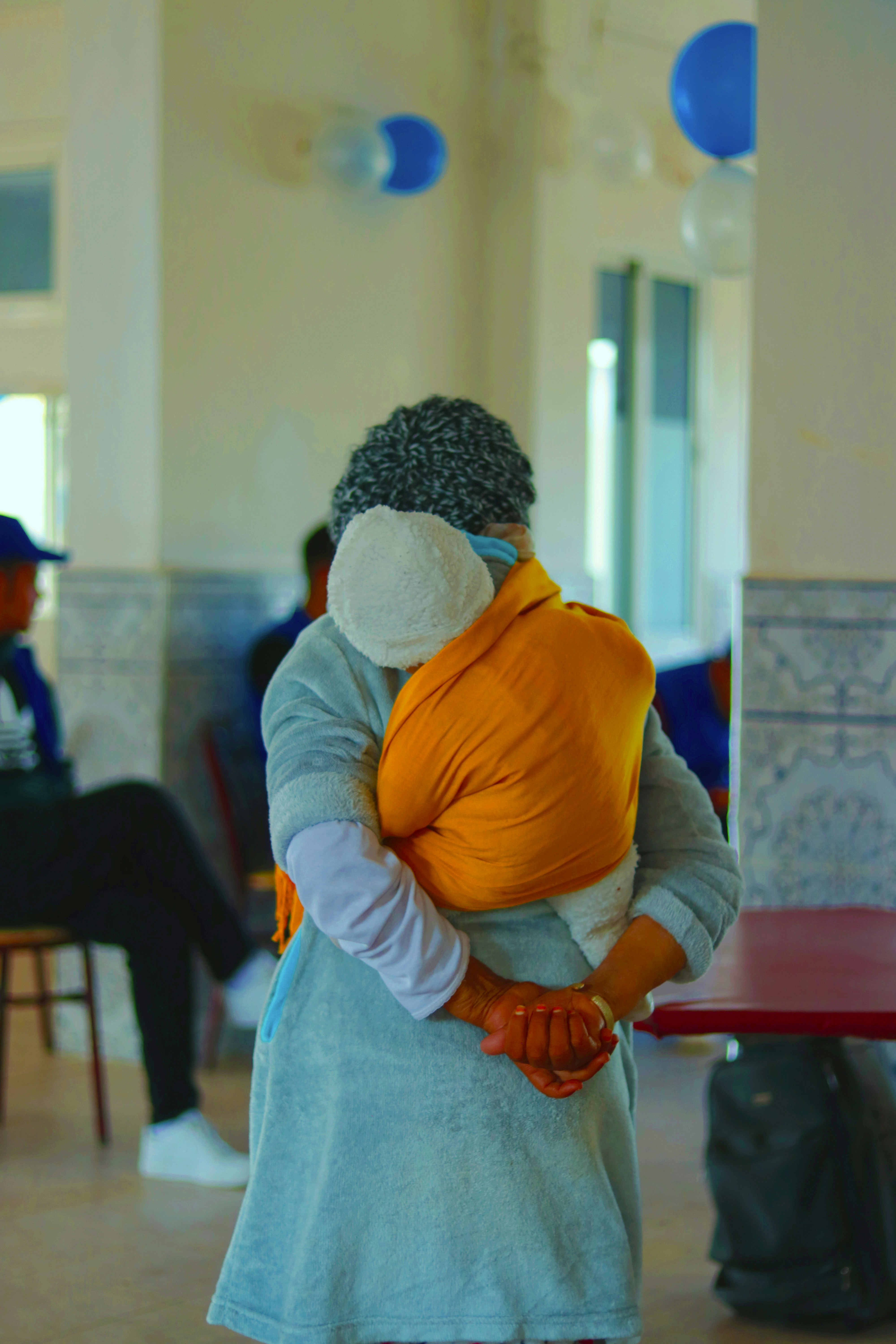 Uma mulher abraça uma criança em uma sala iluminada.