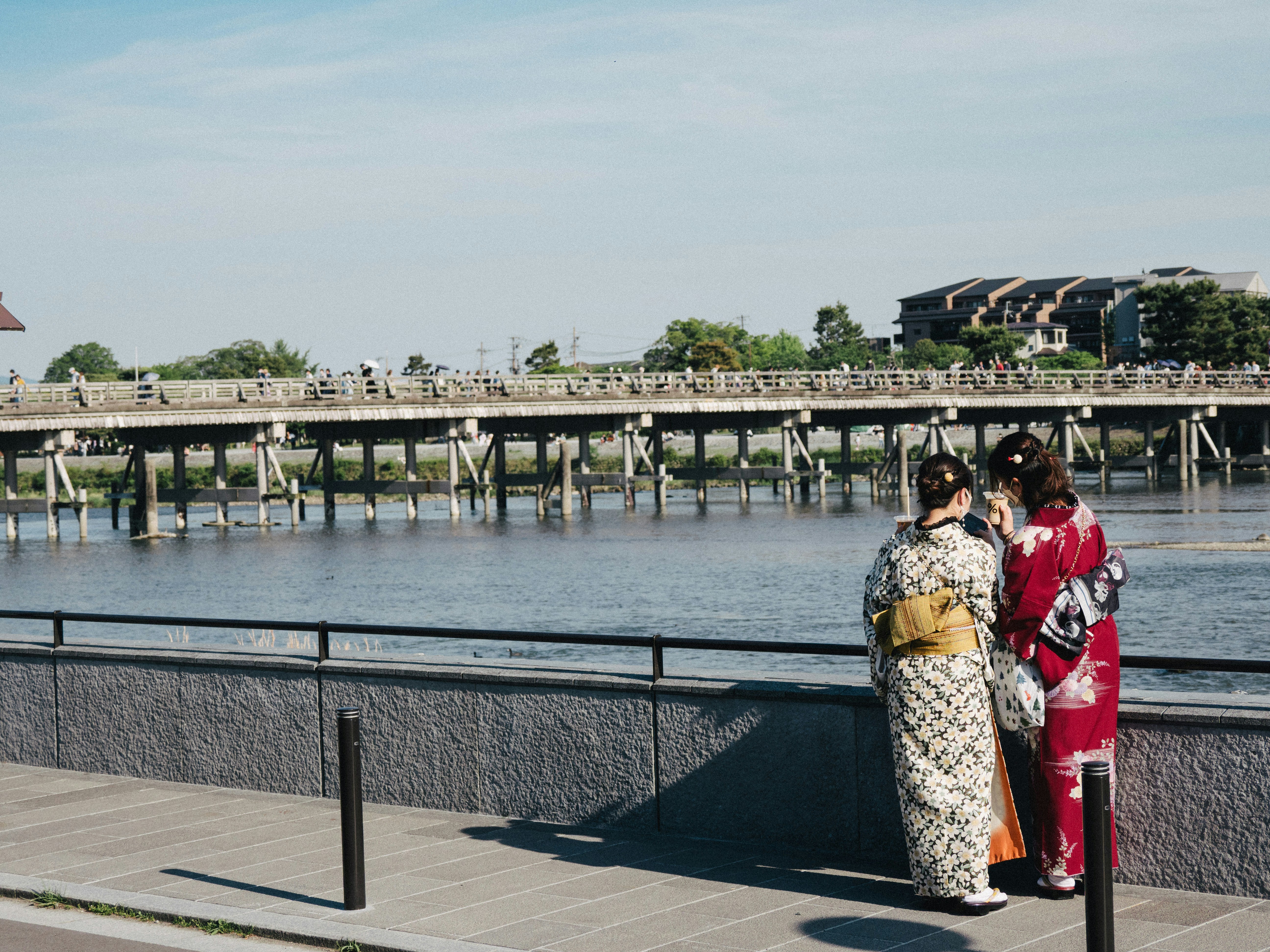 Two women in kimonos look at a bridge.