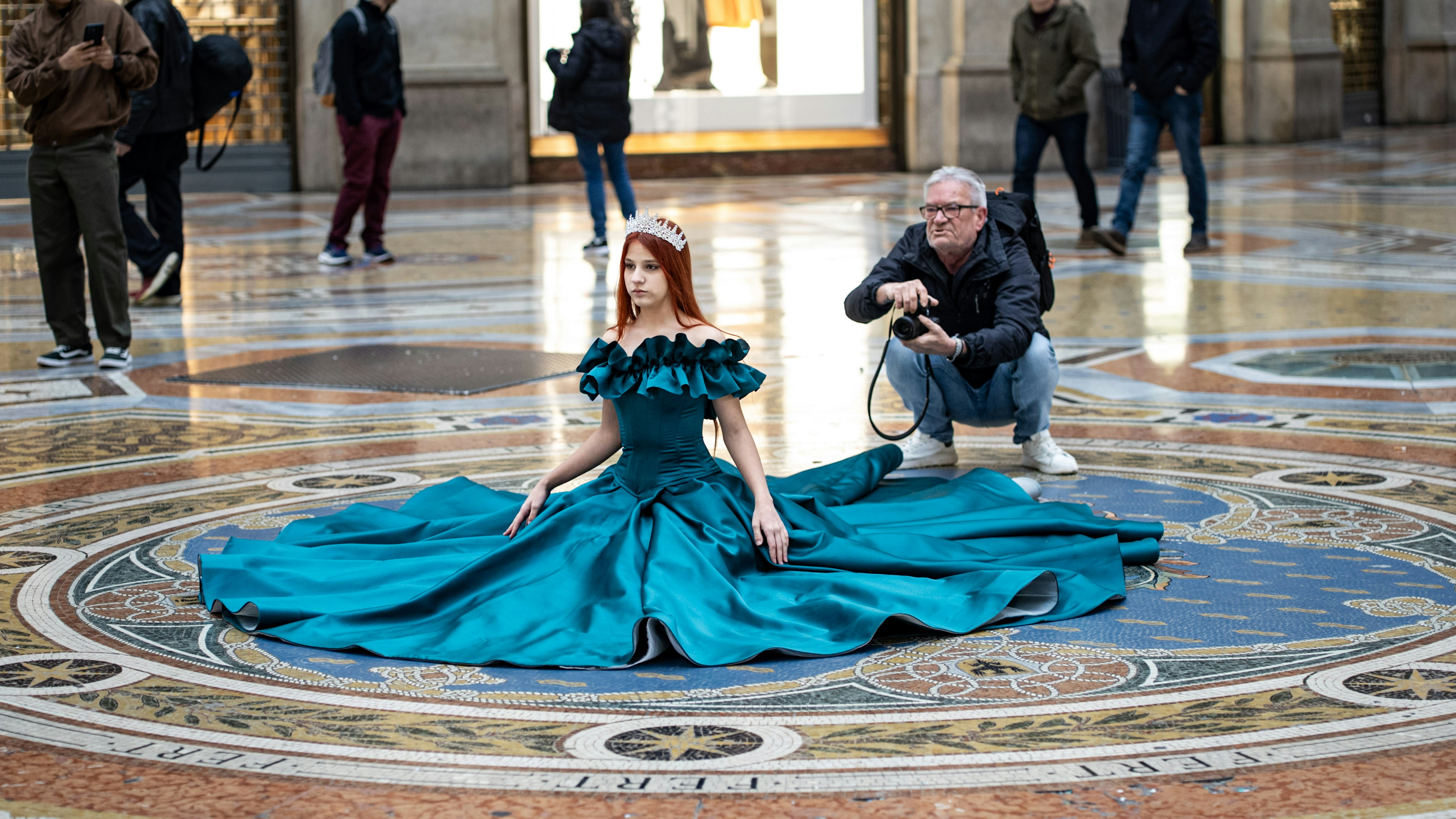 A woman poses in a dress, being photographed.