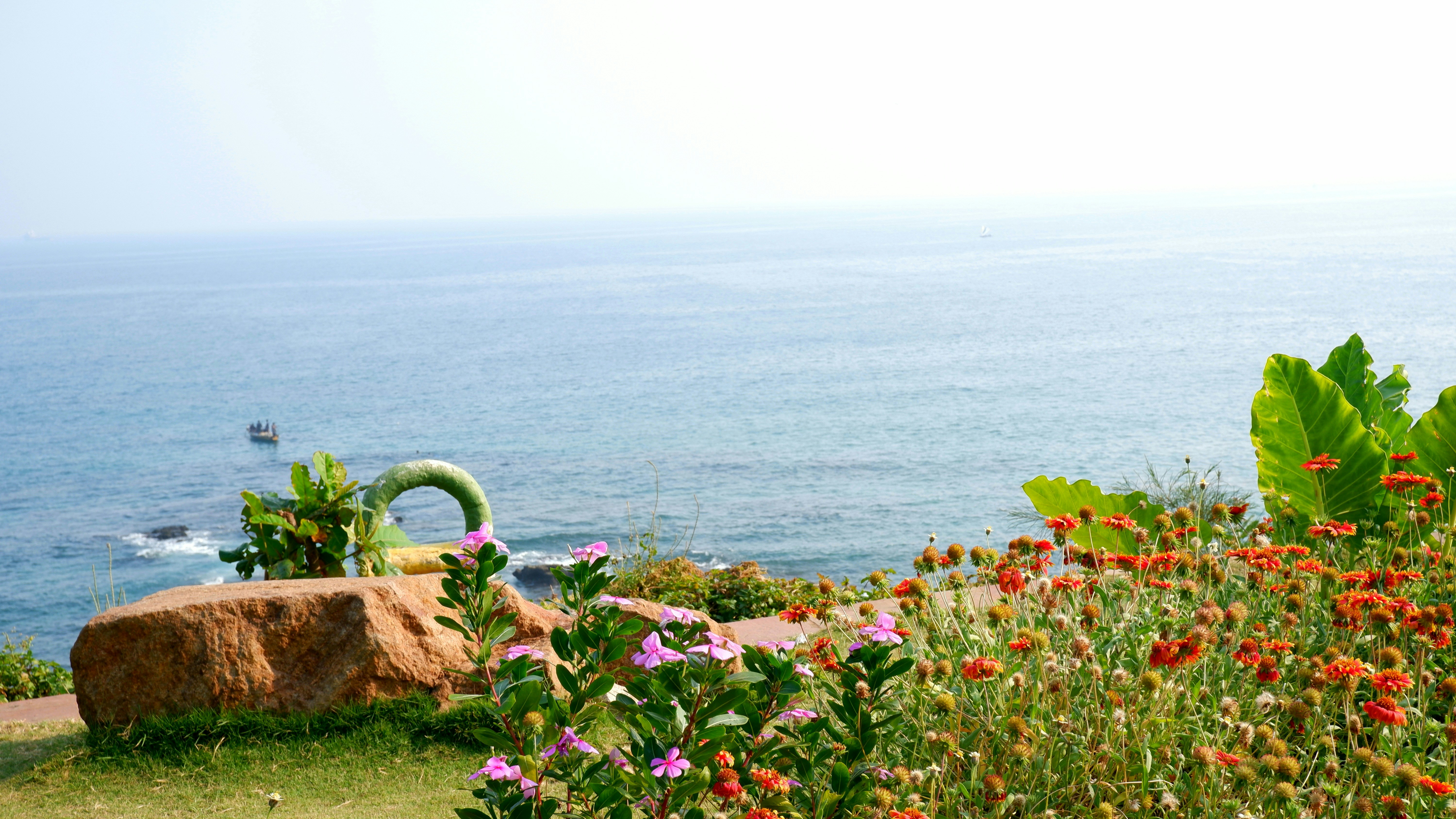 Flowers and rocks overlook the vast blue ocean.