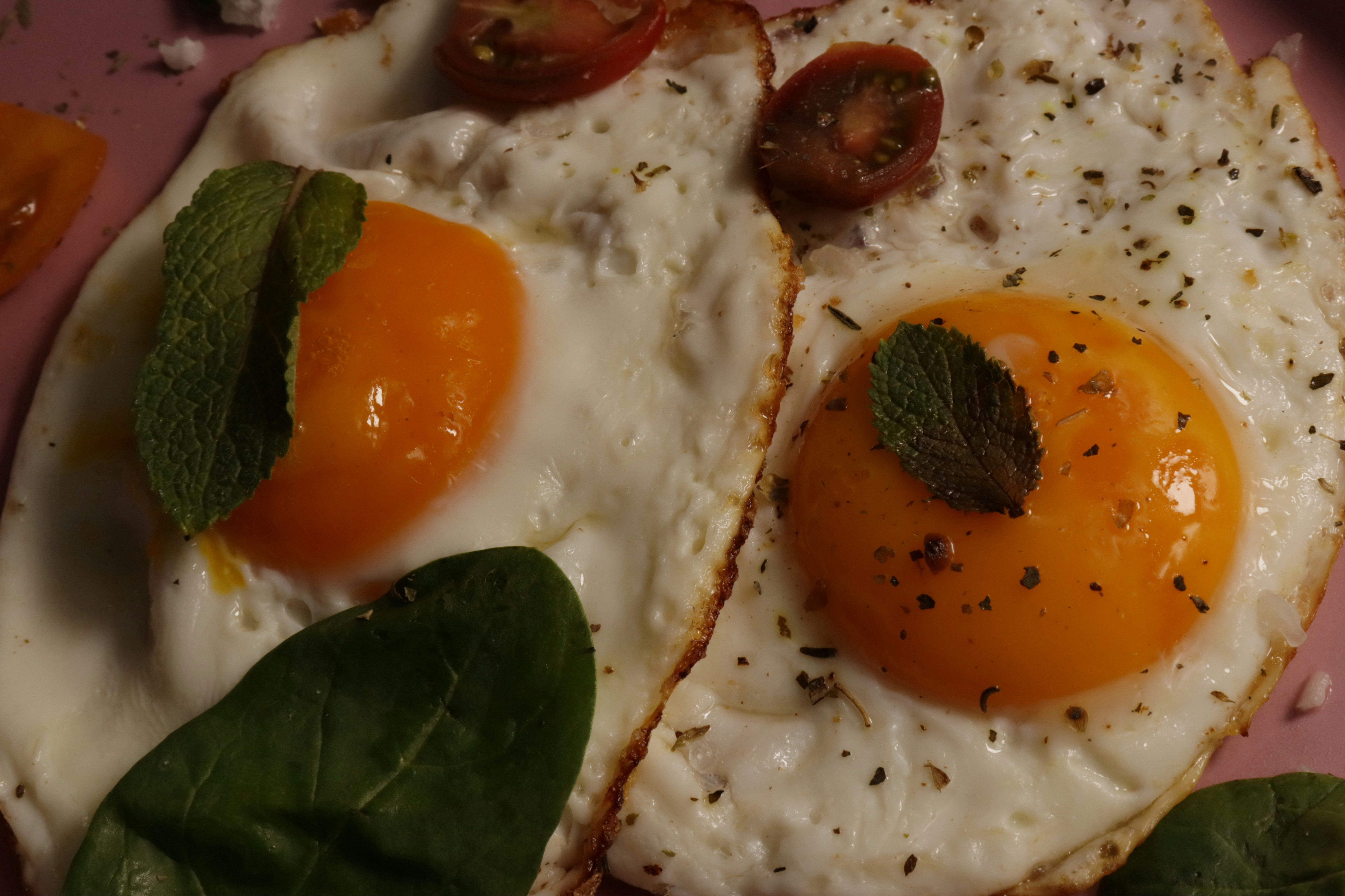 Two sunny-side-up eggs, served with mint and tomato.
