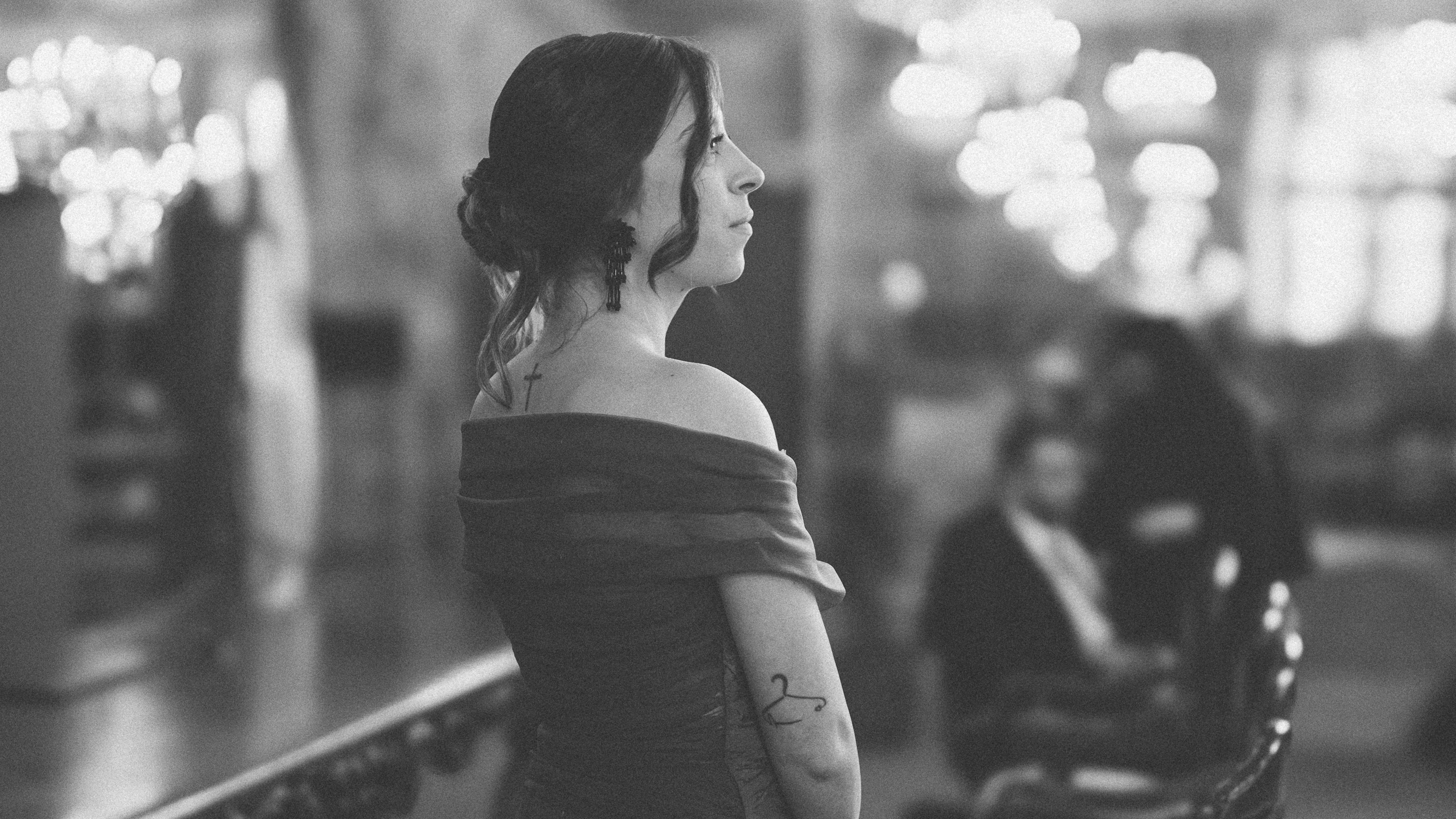 A woman in a dress gazes thoughtfully.