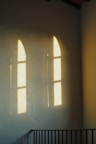 Shadows of arched windows reflect on a wall.