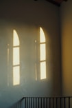 Shadows of arched windows reflect on a wall.