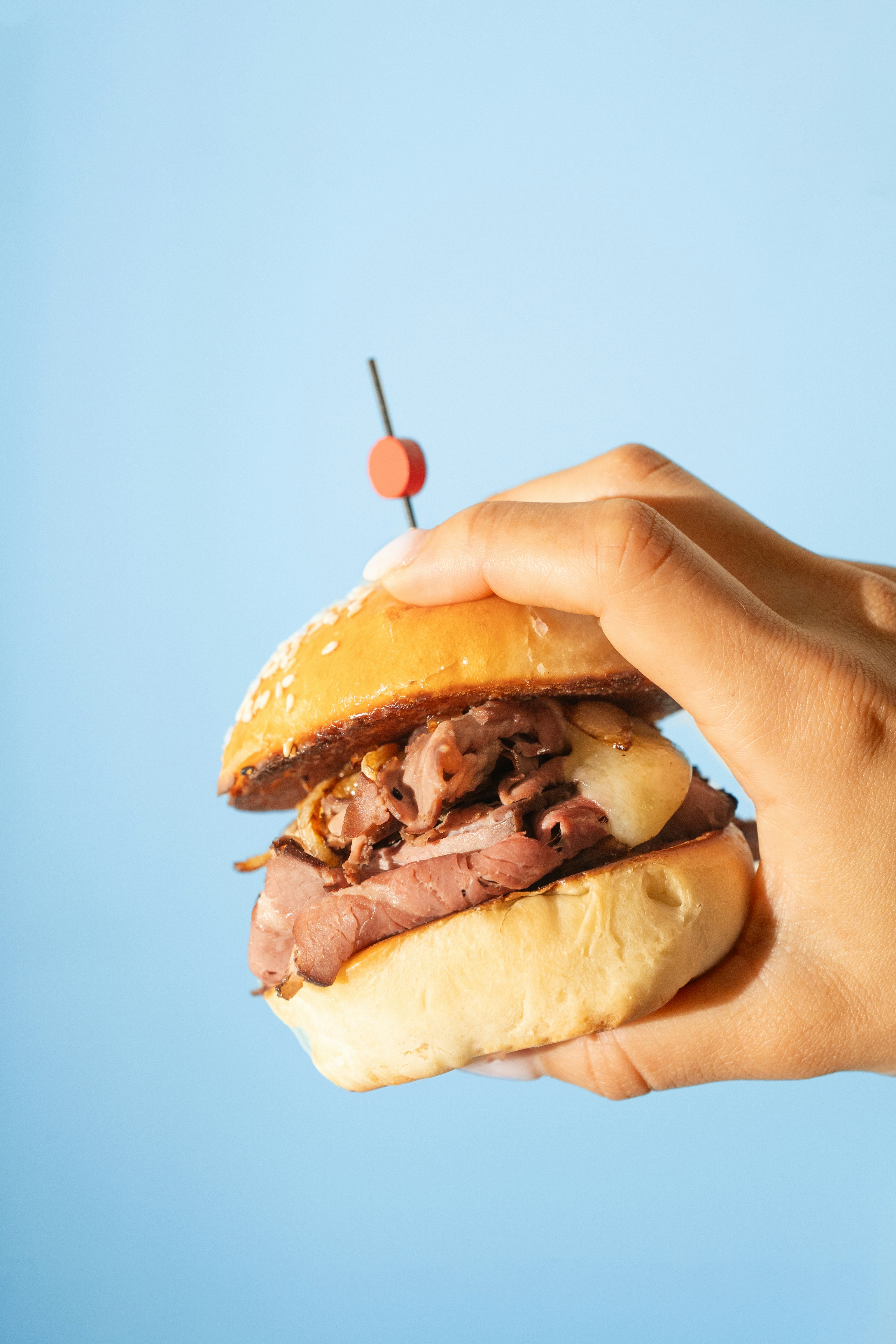 A hand holds a delicious beef sandwich.
