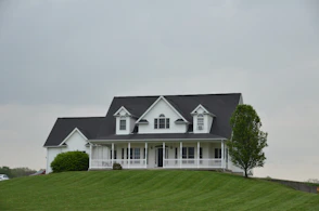 A white house sits atop a green hill.