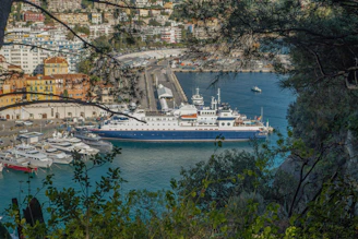 A large ship docks in a beautiful coastal city.