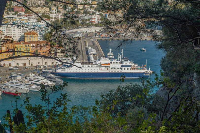 A large ship docks in a beautiful coastal city.