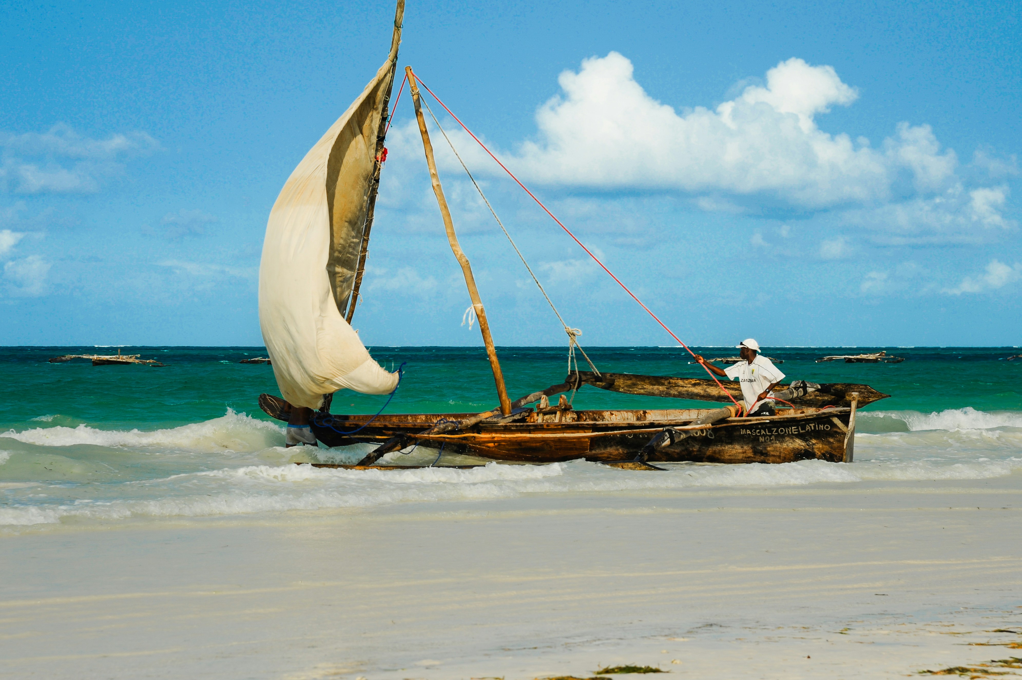 A sailboat rests on a sandy beach.