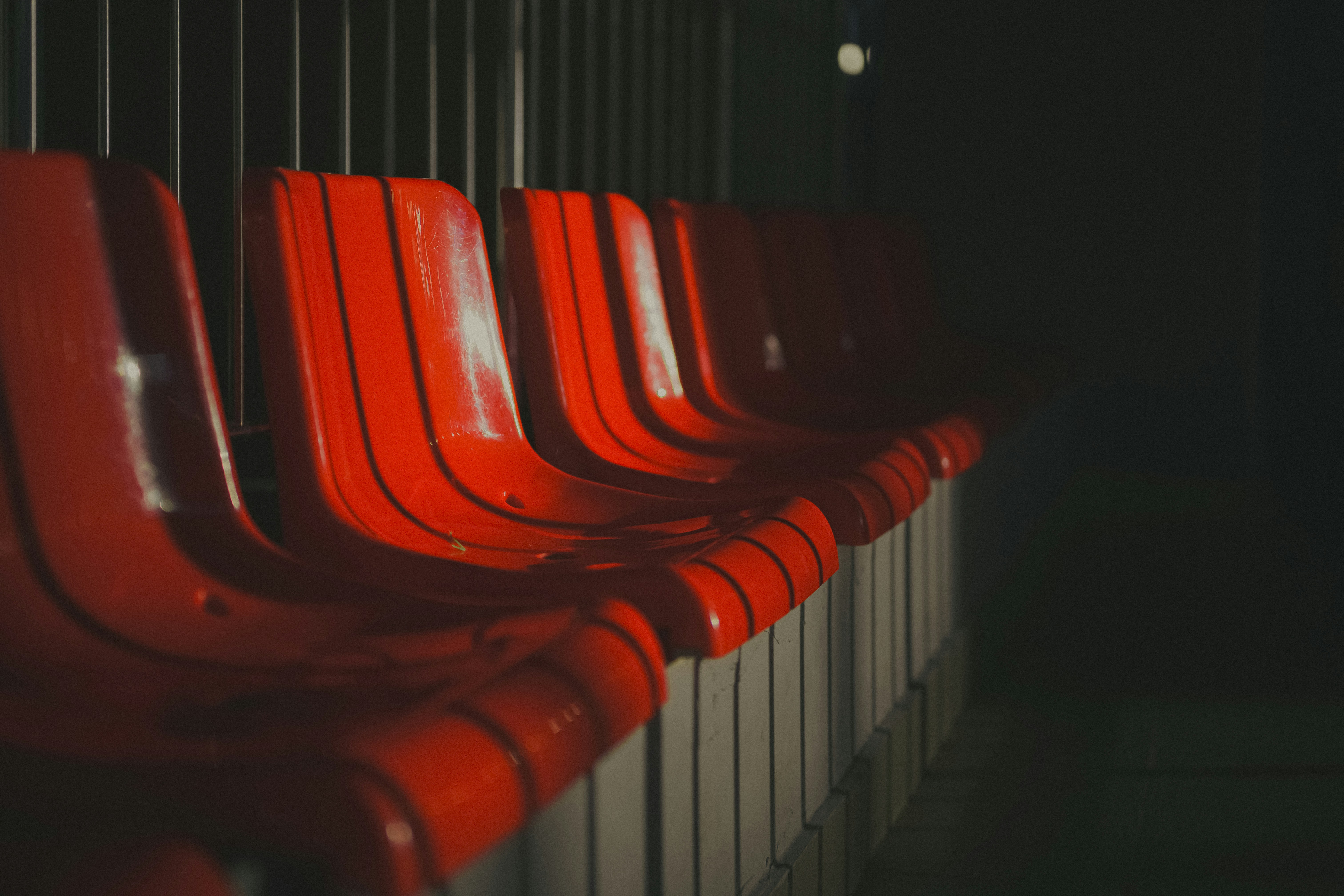 Red stadium seats are illuminated in the darkness.
