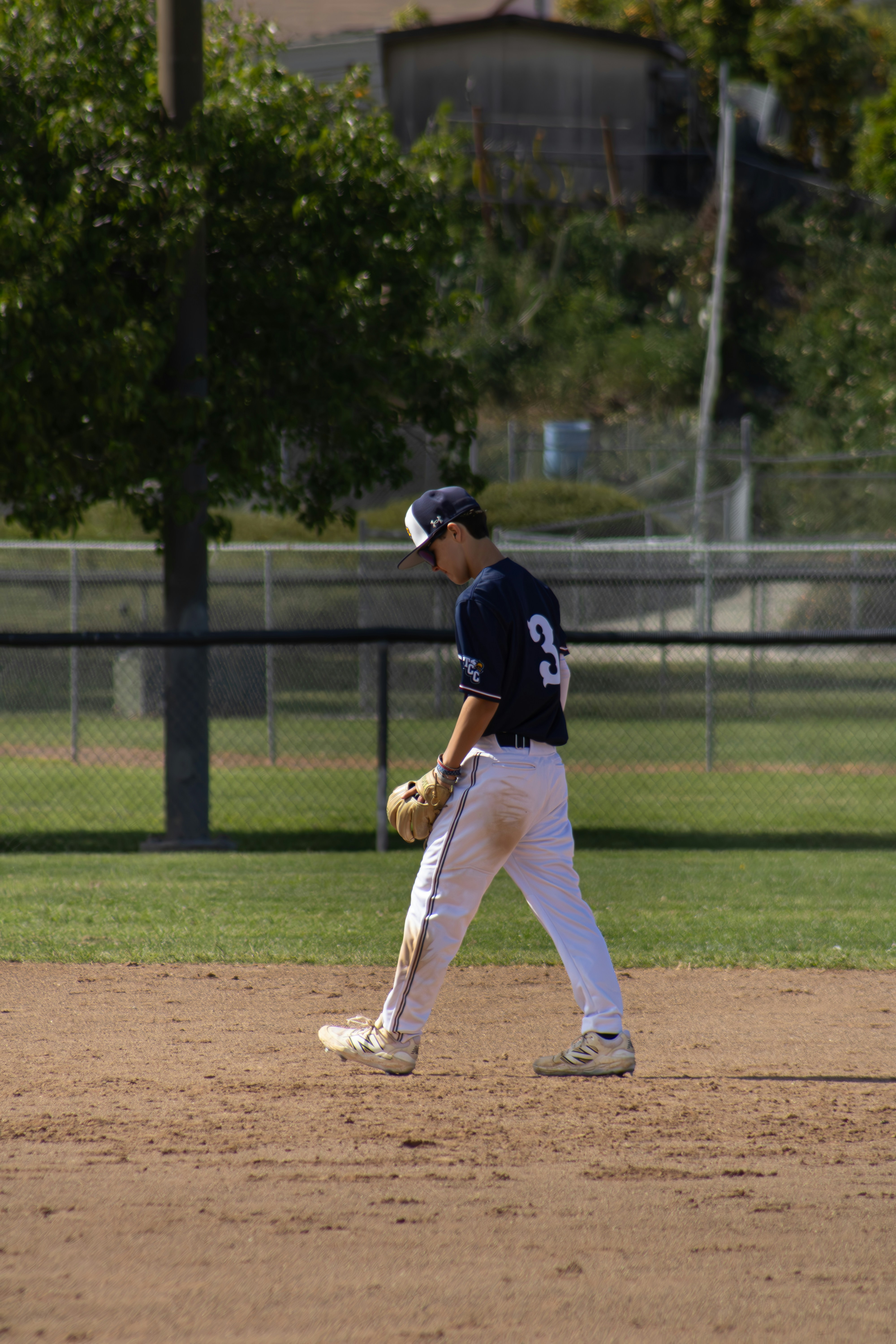 A baseball player walks dejectedly across the infield.