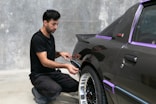 A man is working on a car's paint.