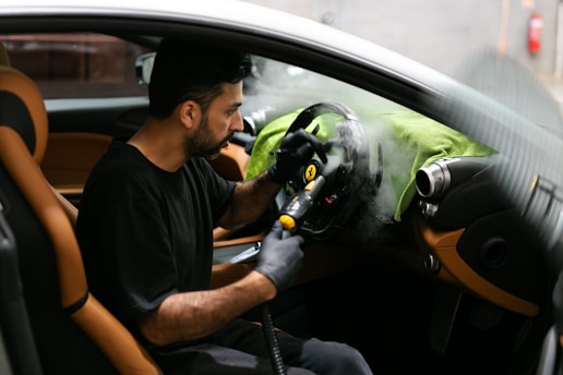 Man steam-cleans the interior of a car.