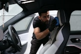 A man cleans a car seat inside the vehicle.