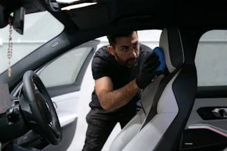 A man cleans a car seat inside the vehicle.