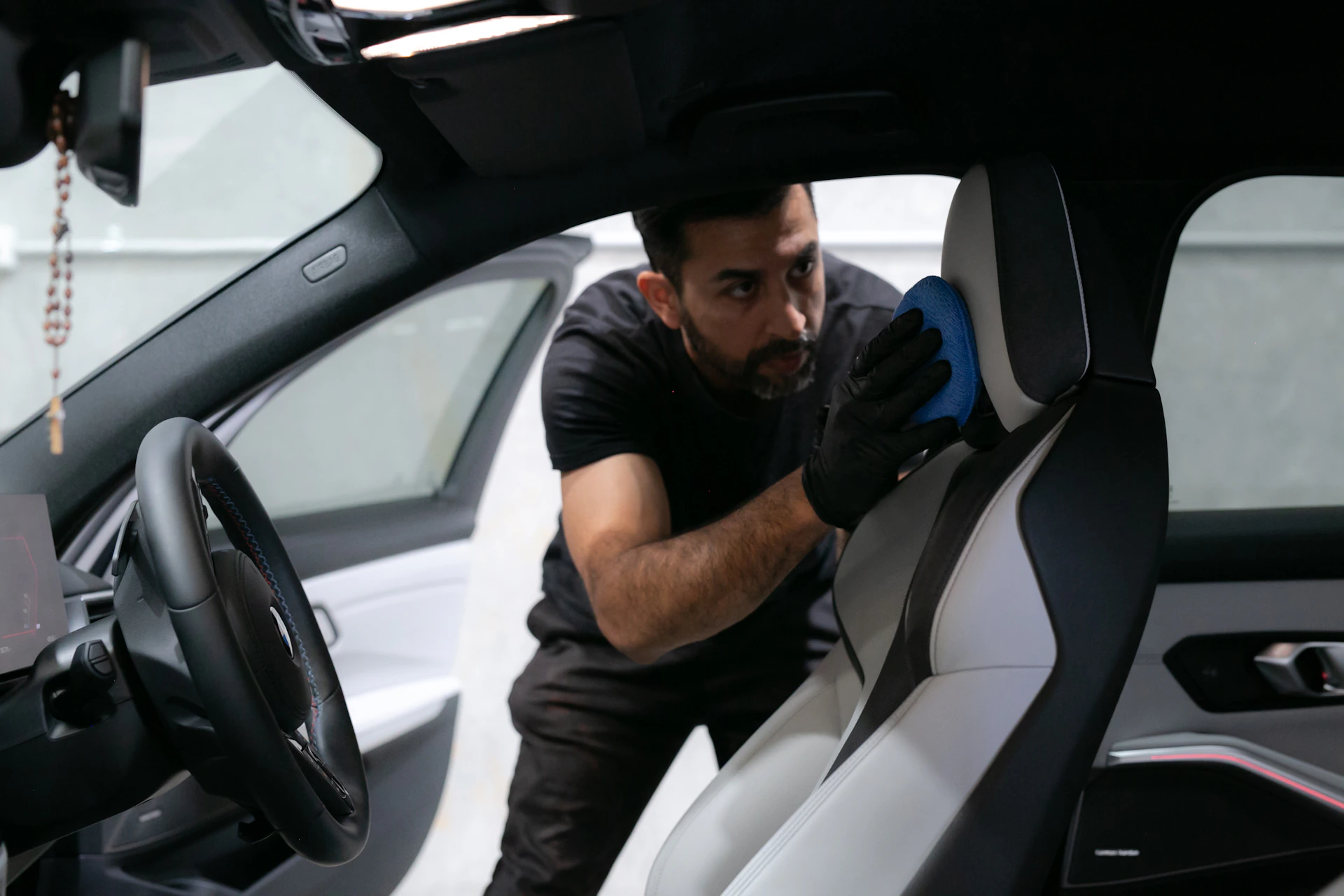 A man cleans a car seat inside the vehicle.