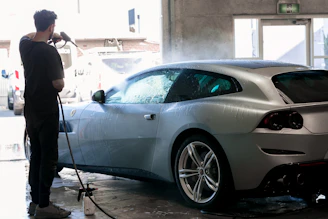 Man washes a silver car in a car wash.