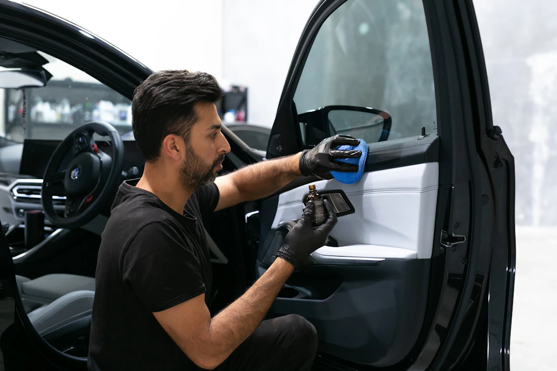 Detailer cleaning the interior door of a vehicle