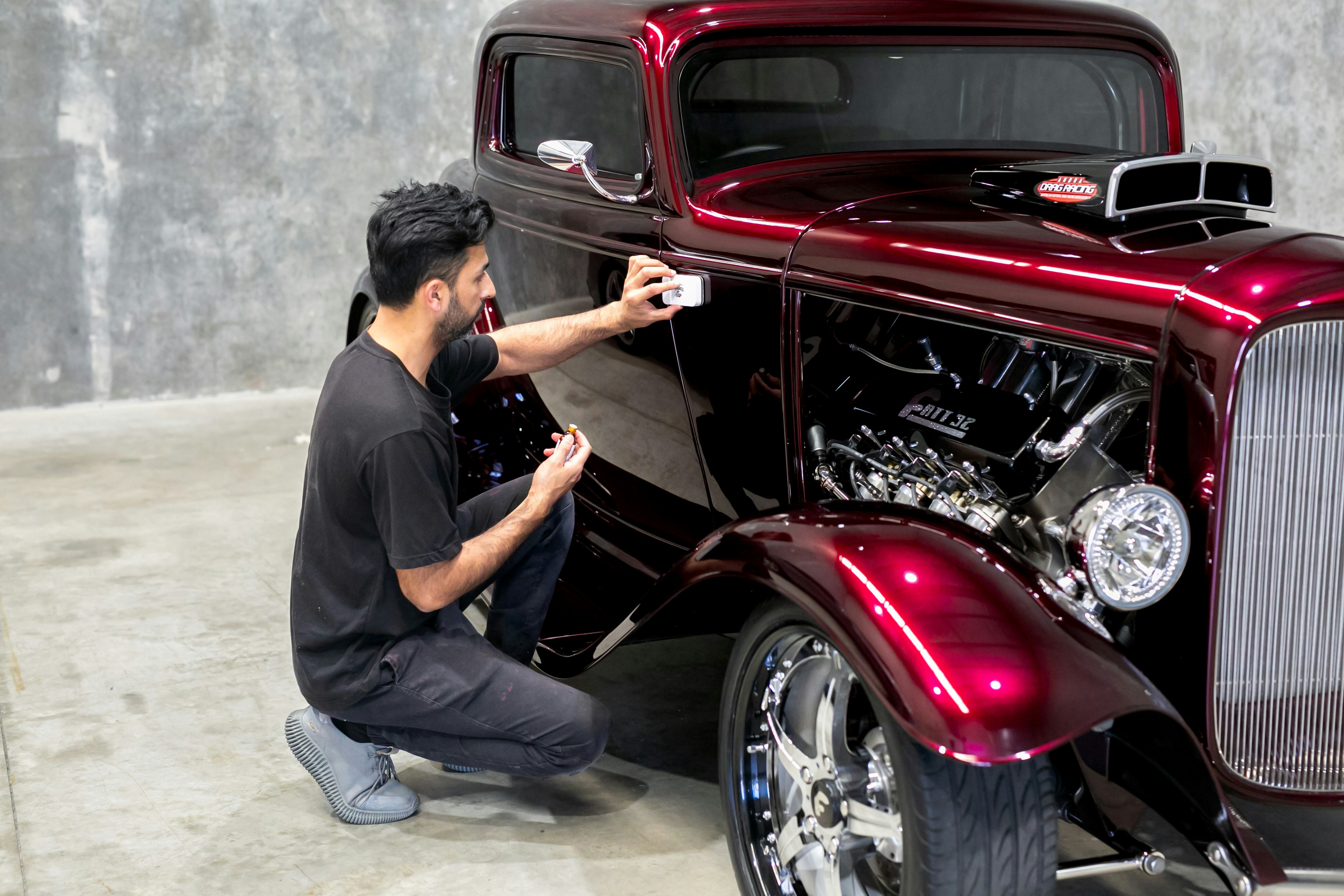 Man takes a photo of a shiny, red hot rod.
