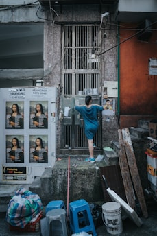 A woman stands by a grated door.
