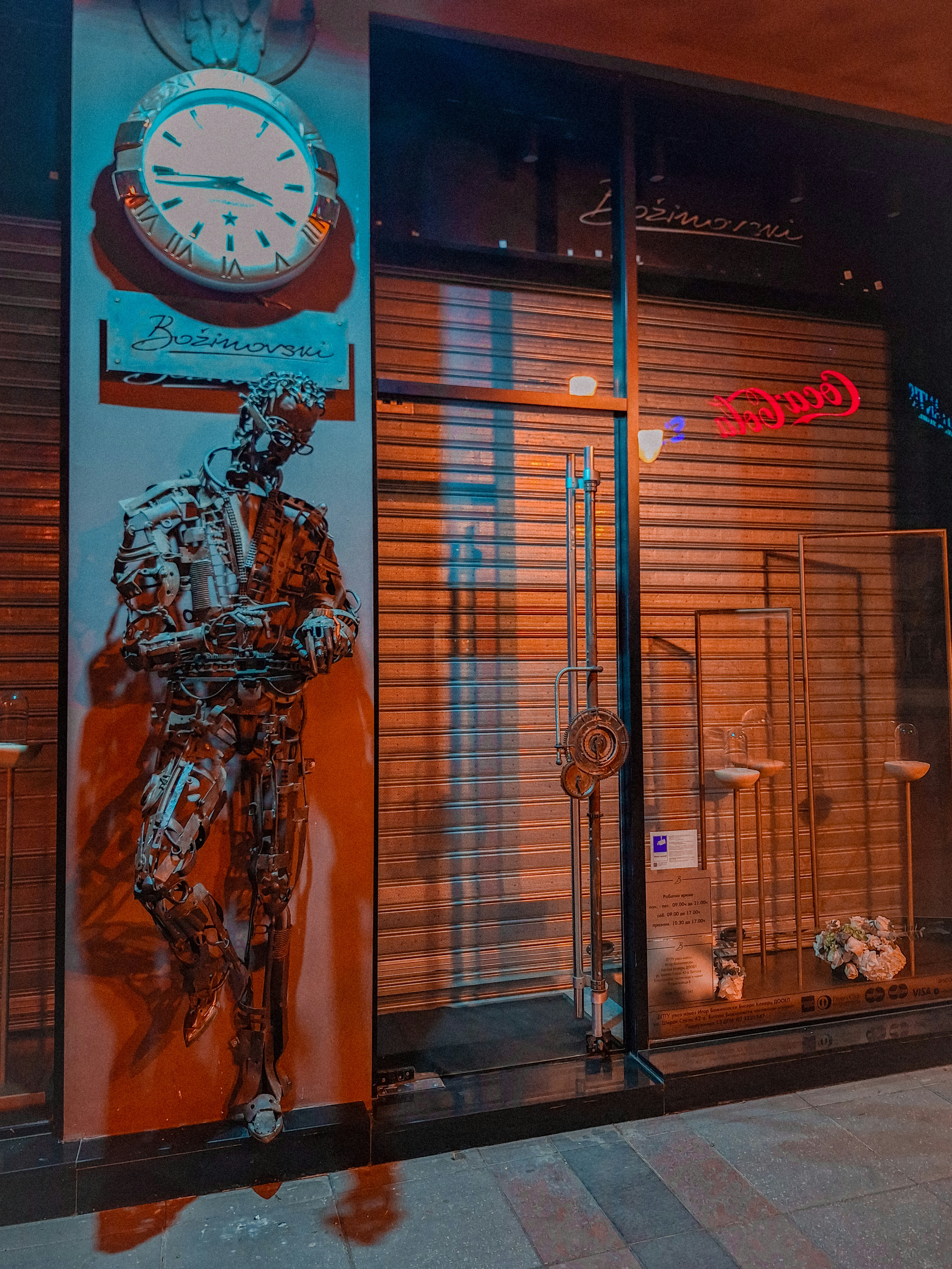 A storefront showcases art and a closed shutter.