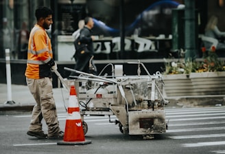 A worker paints crosswalk lines on the street.