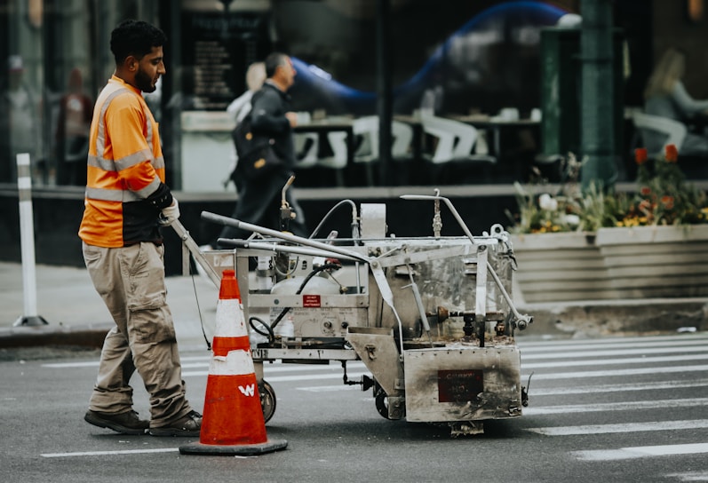 A worker paints crosswalk lines on the street.