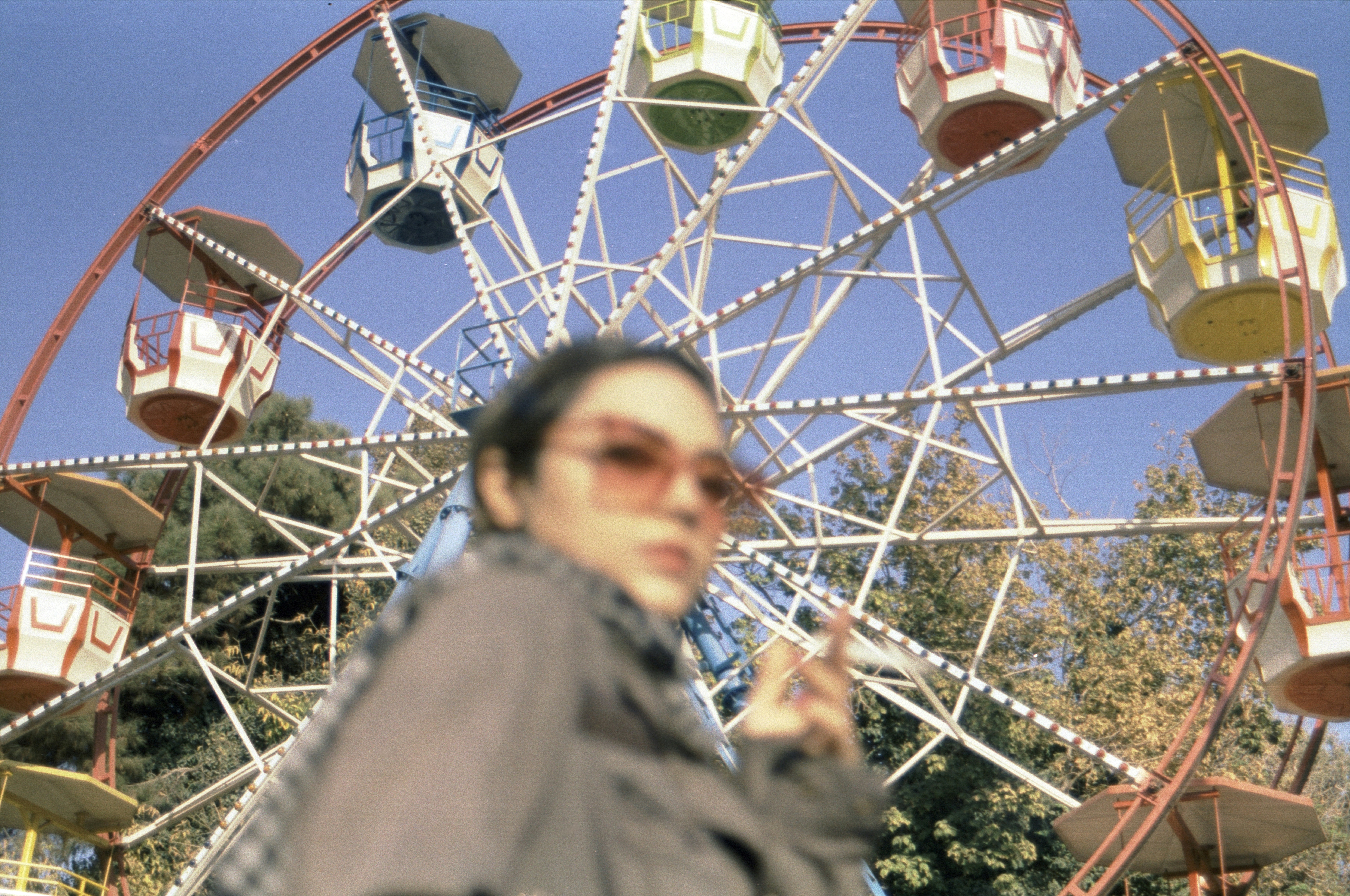 Woman stands in front of a colorful ferris wheel.