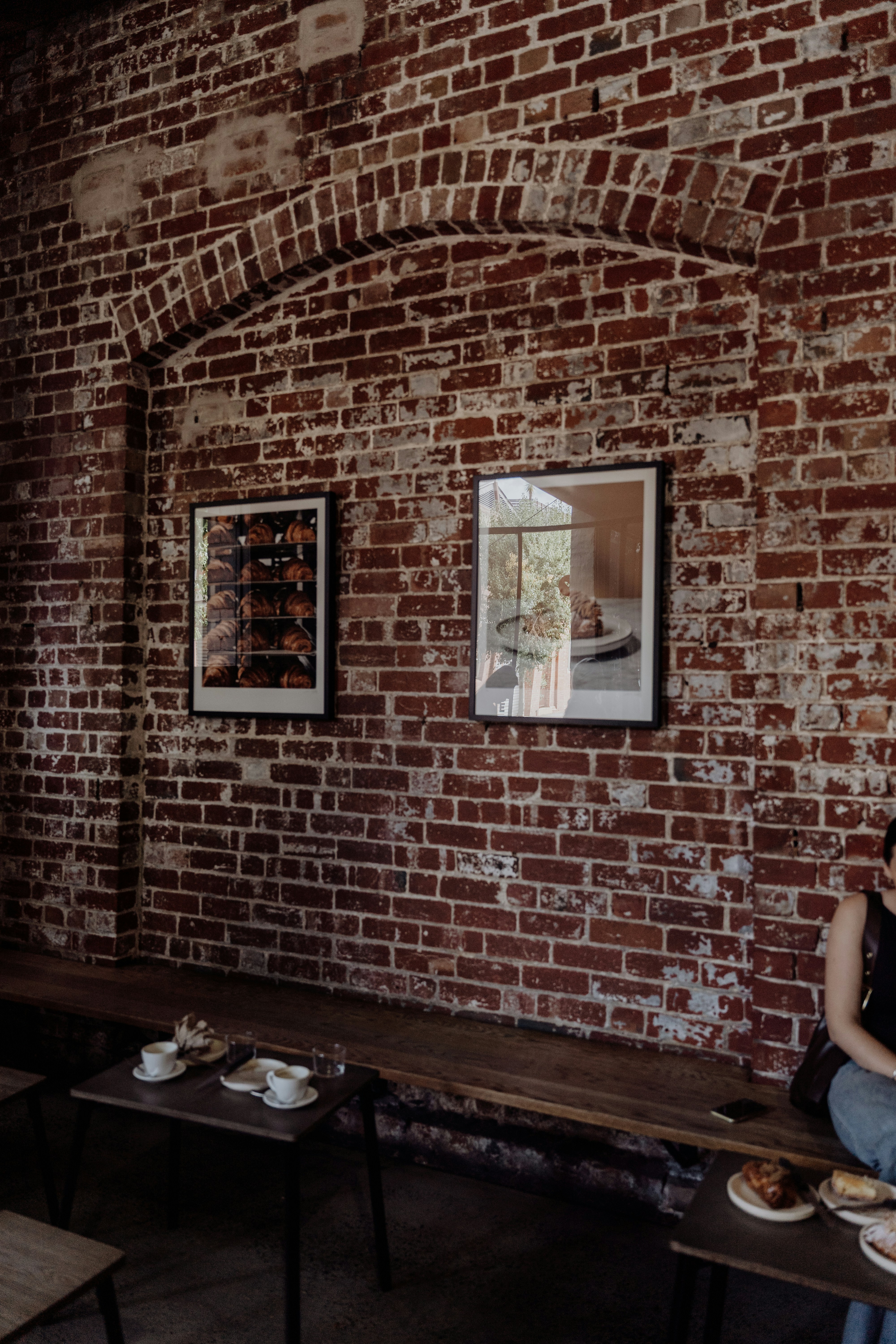 An old brick wall with two framed pictures.