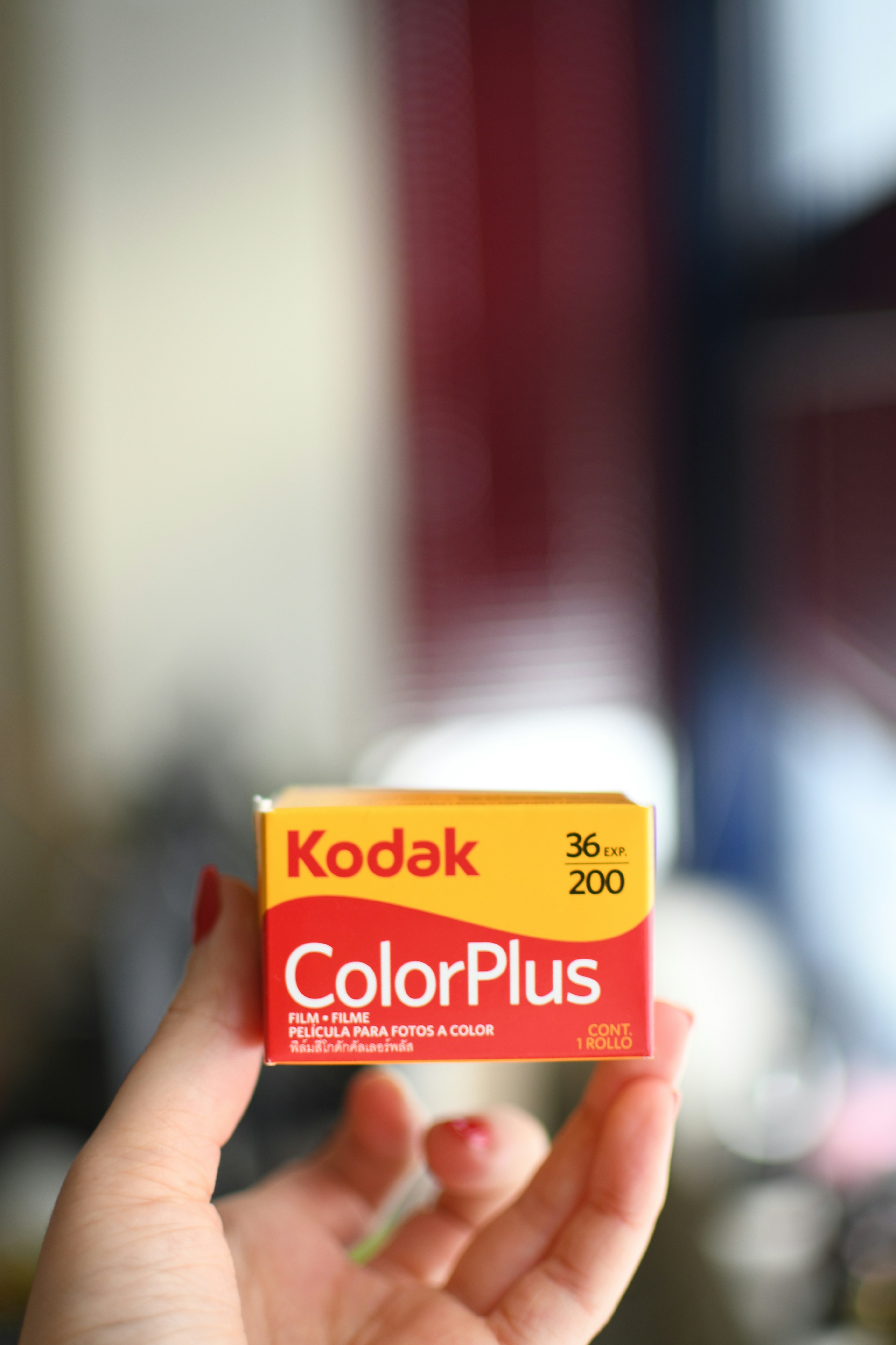 A hand holds a kodak colorplus film roll.