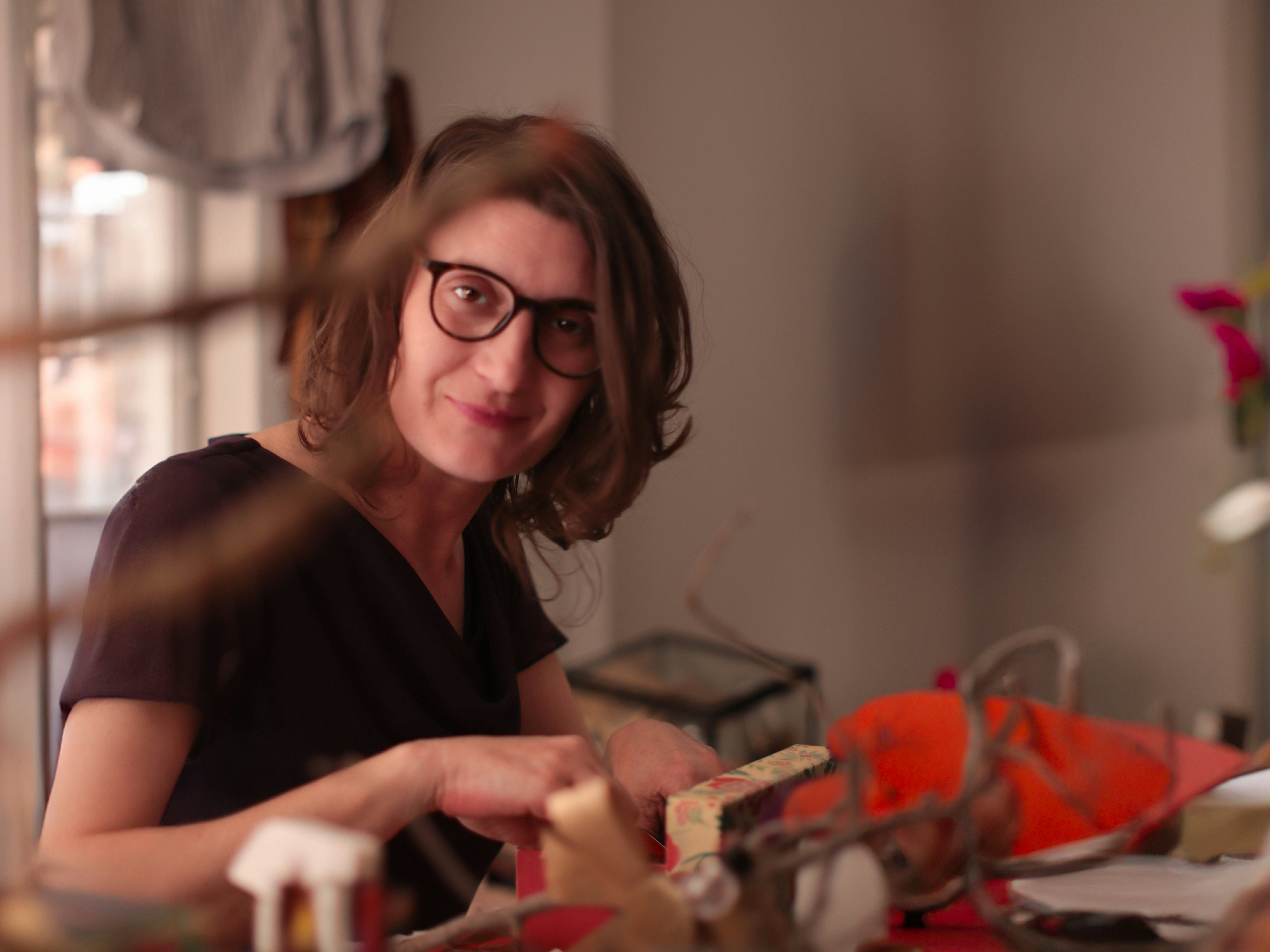 Uma mulher com óculos olha para a câmera.