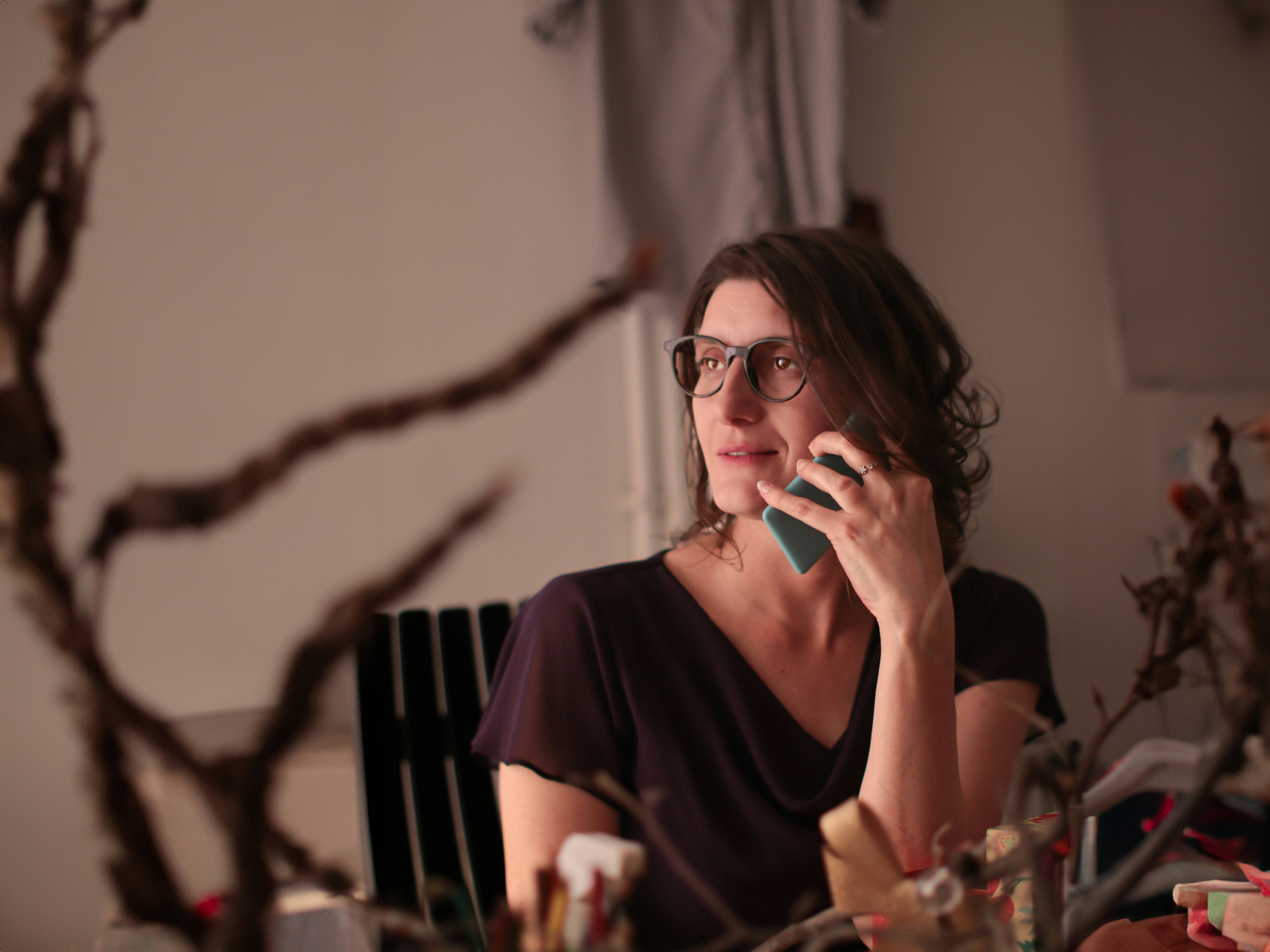 Mulher com óculos fala ao telefone.