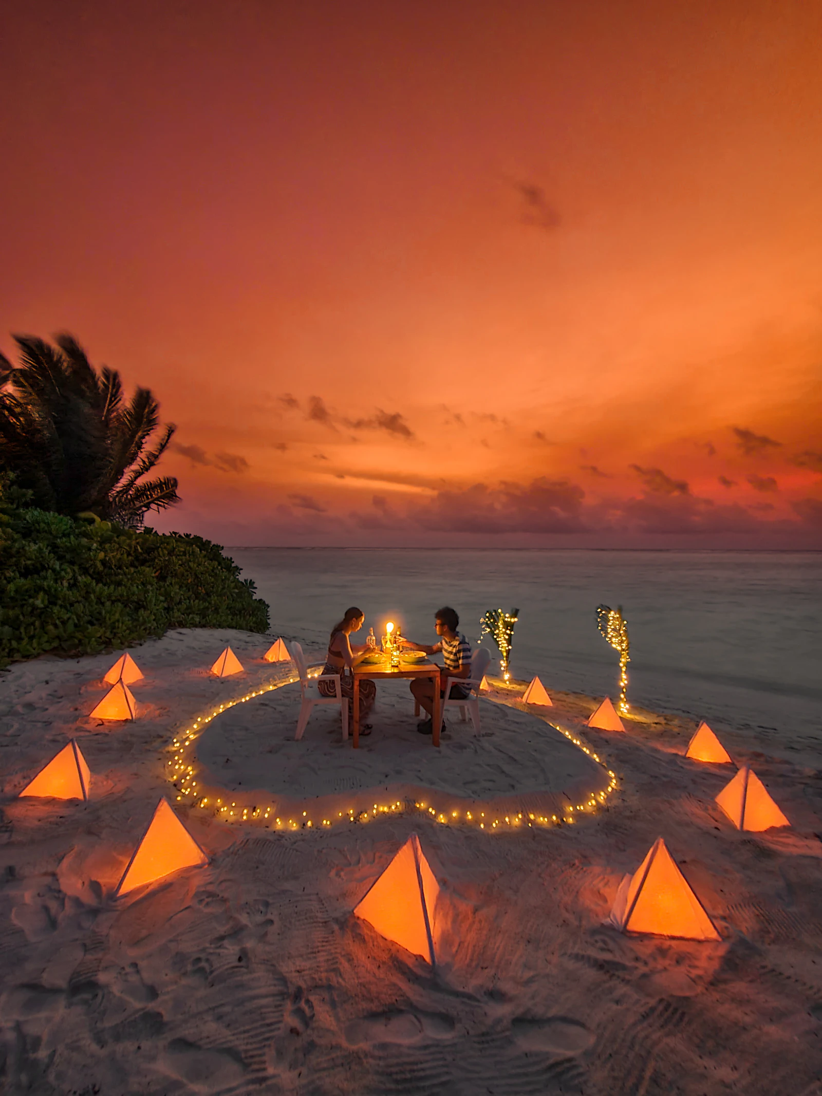 Couple enjoying a romantic anniversary dinner on a beach at sunset