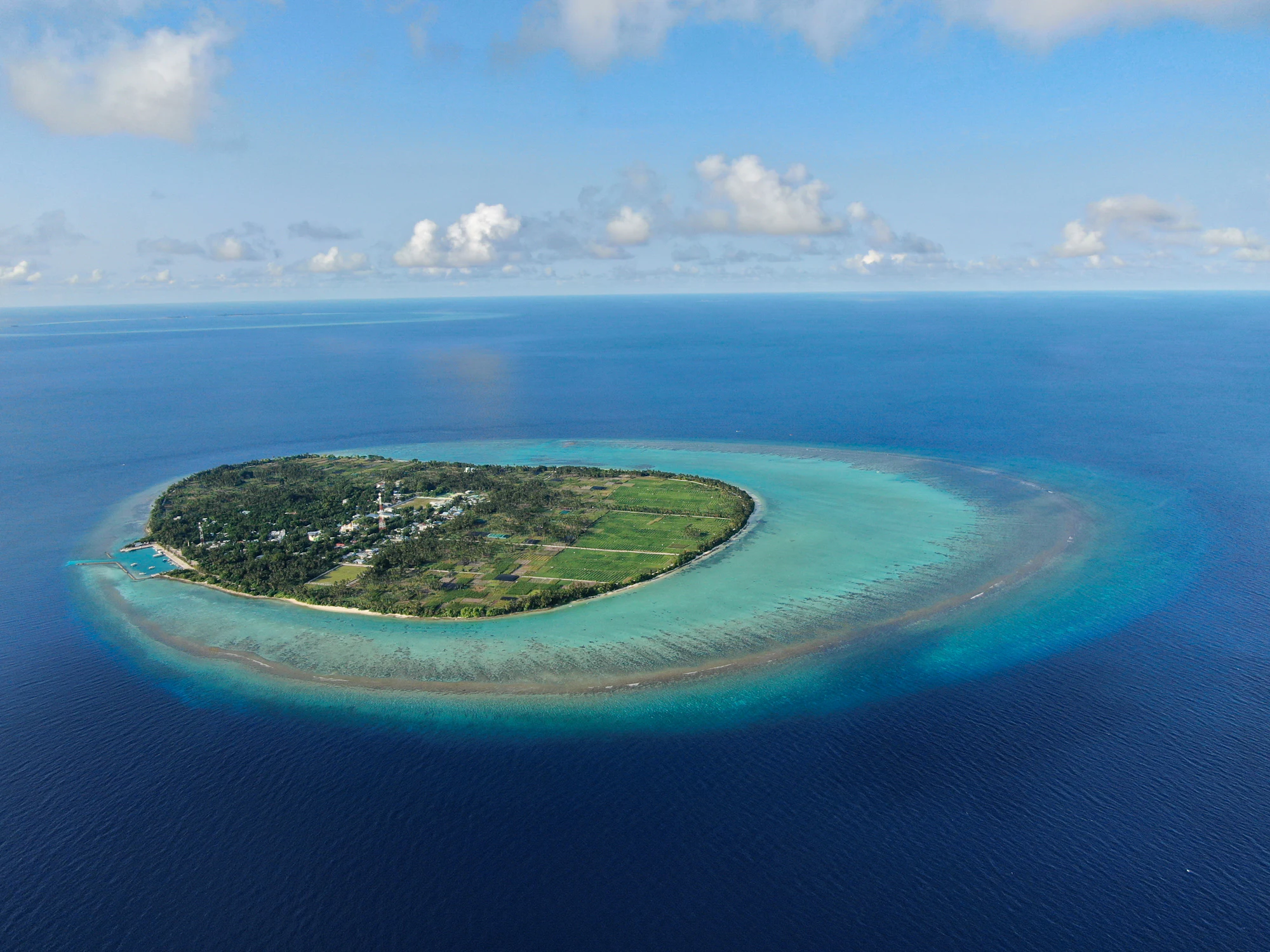 A small island surrounded by reef and turquoise water in the Maldives