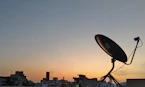 A satellite dish watches the sunset over the city.