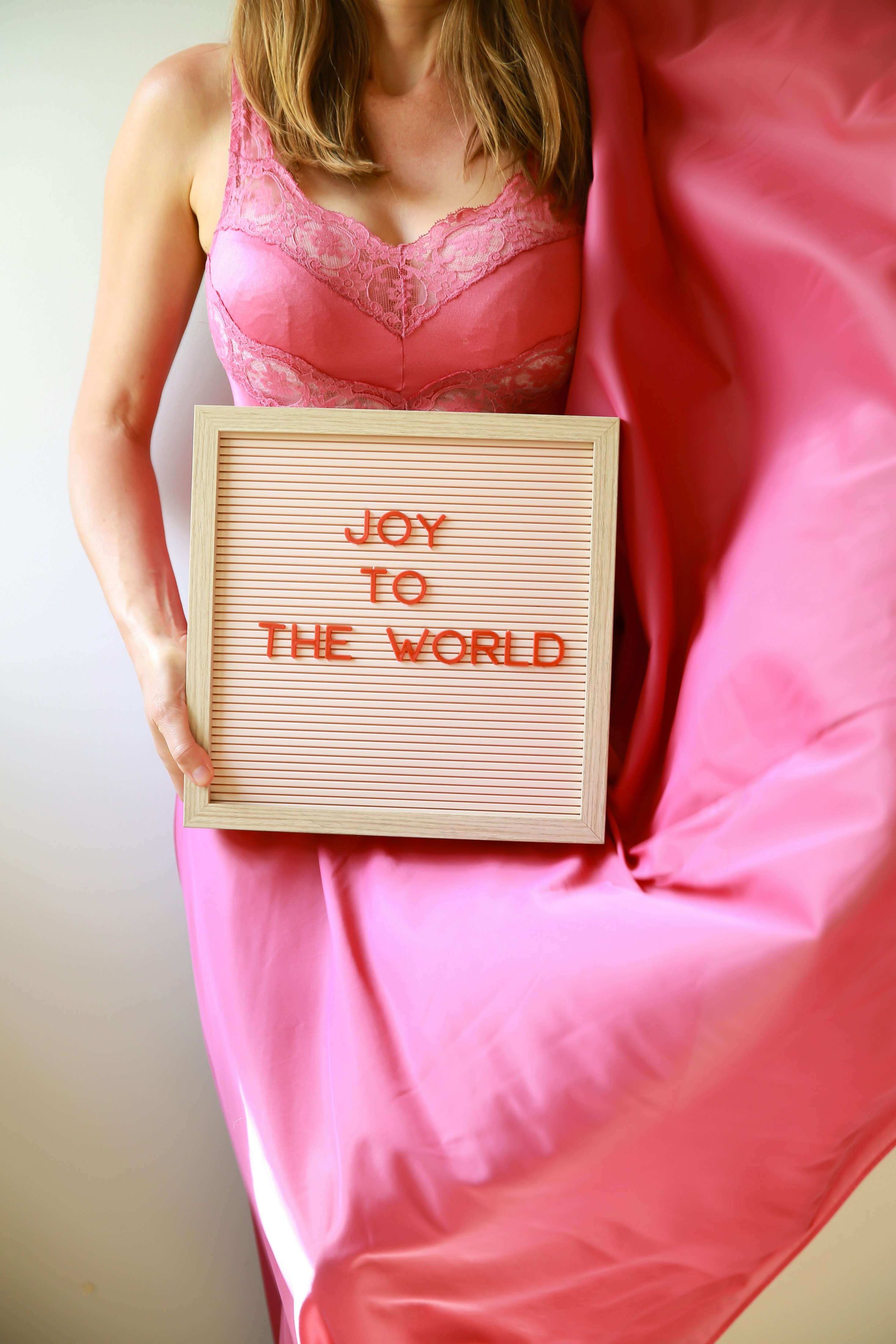 Woman holds a sign saying "joy to the world."