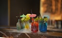 Colorful cocktails are served on a smoked countertop.