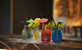Colorful cocktails are served on a smoked countertop.