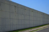 Concrete wall stretches along a grassy slope.