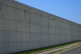 Concrete wall stretches along a grassy slope.