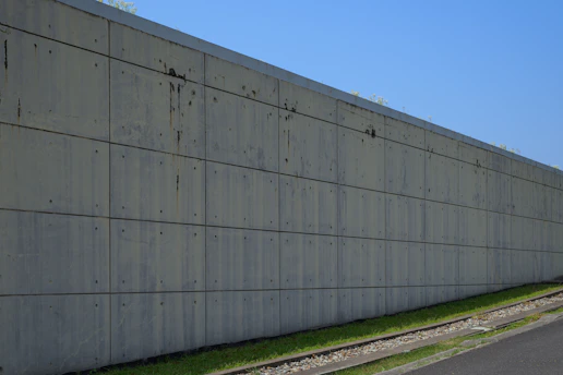 Concrete wall stretches along a grassy slope.