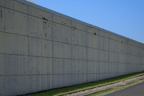 Concrete wall stretches along a grassy slope.