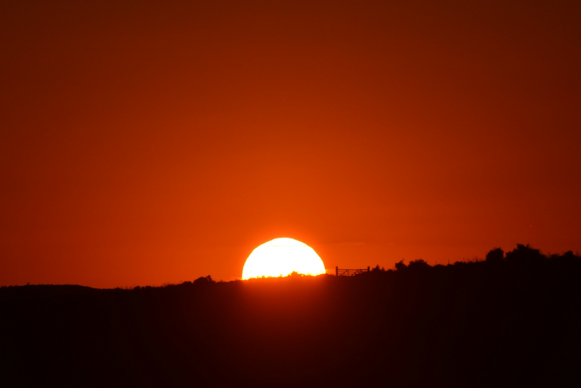 The sun sets with a fiery orange glow.