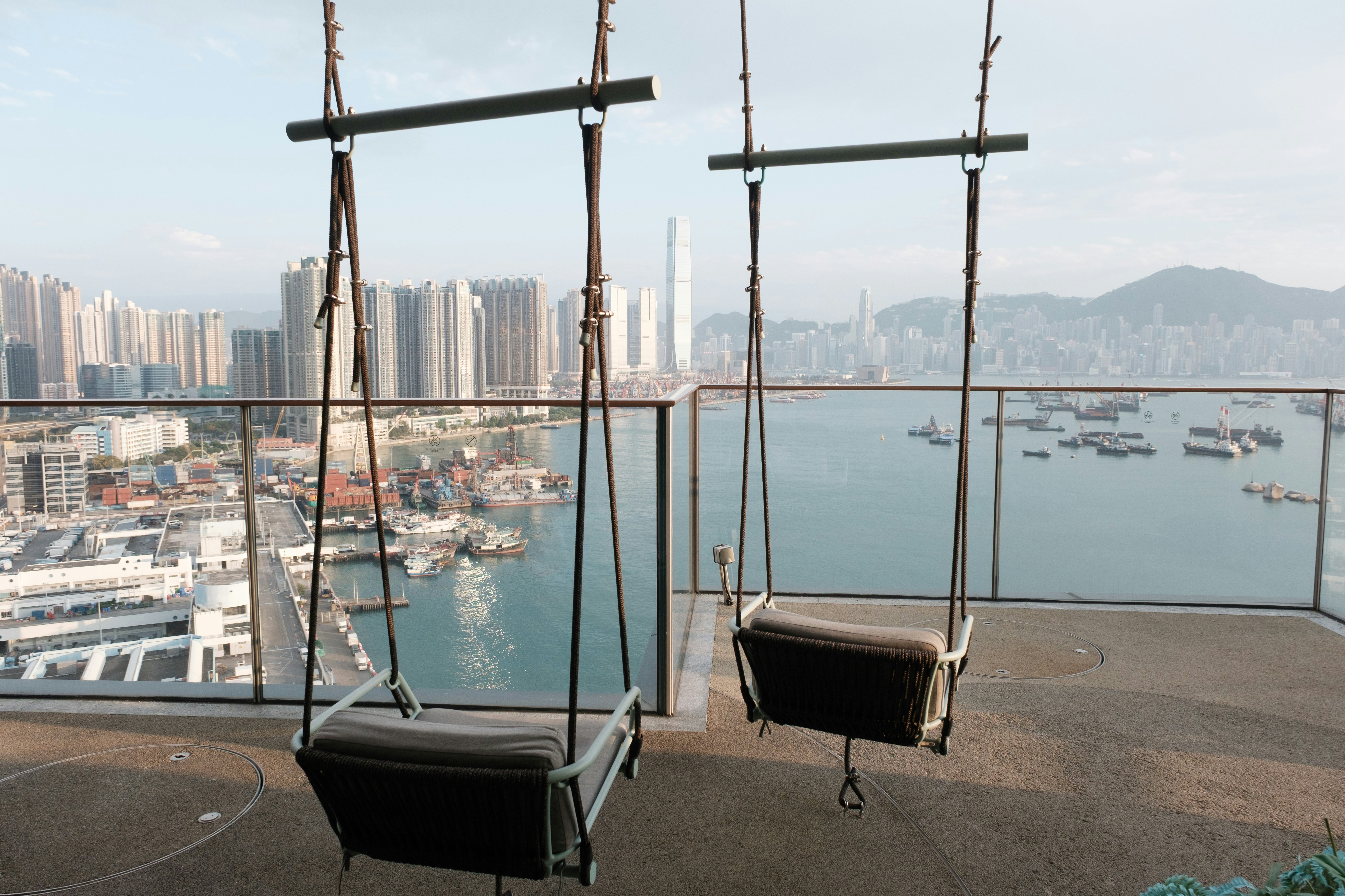 Two swings overlook a scenic cityscape.
