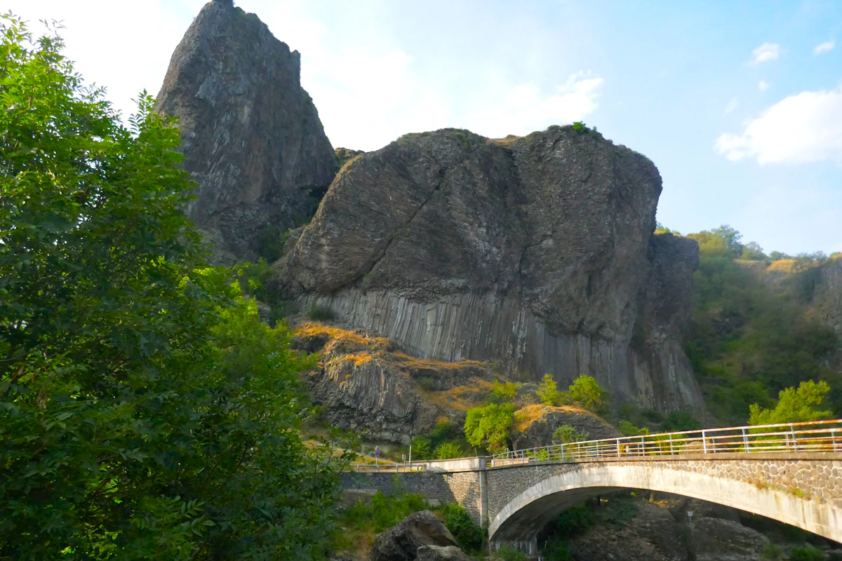 A stone road bridge below dark basalt cliffs at Prades, on the Allier