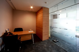 An empty office with a desk and a glass wall.