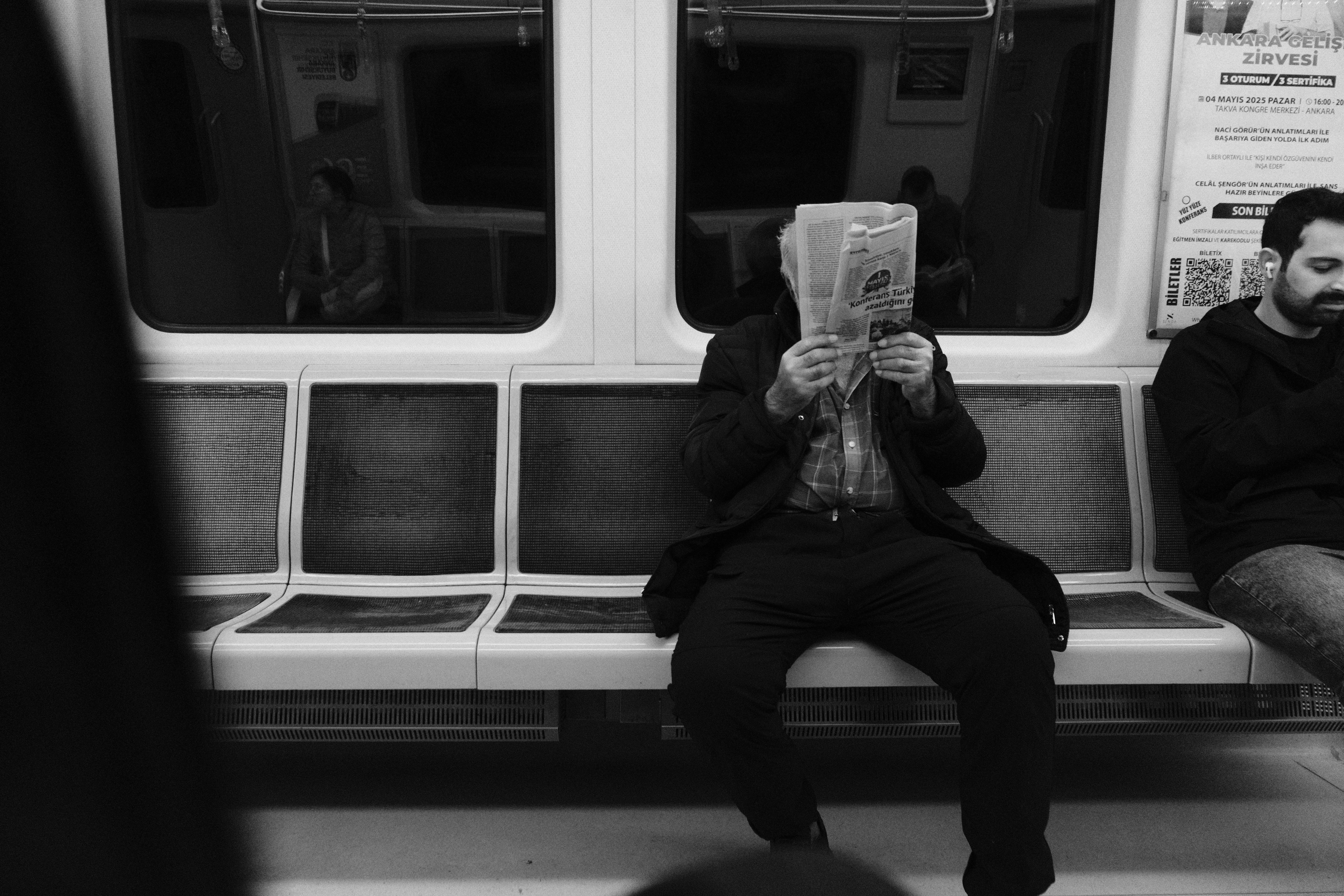 Man reads newspaper on subway.