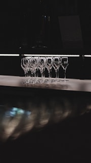Champagne flutes line up in a dark environment.