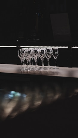 Champagne flutes line up in a dark environment.