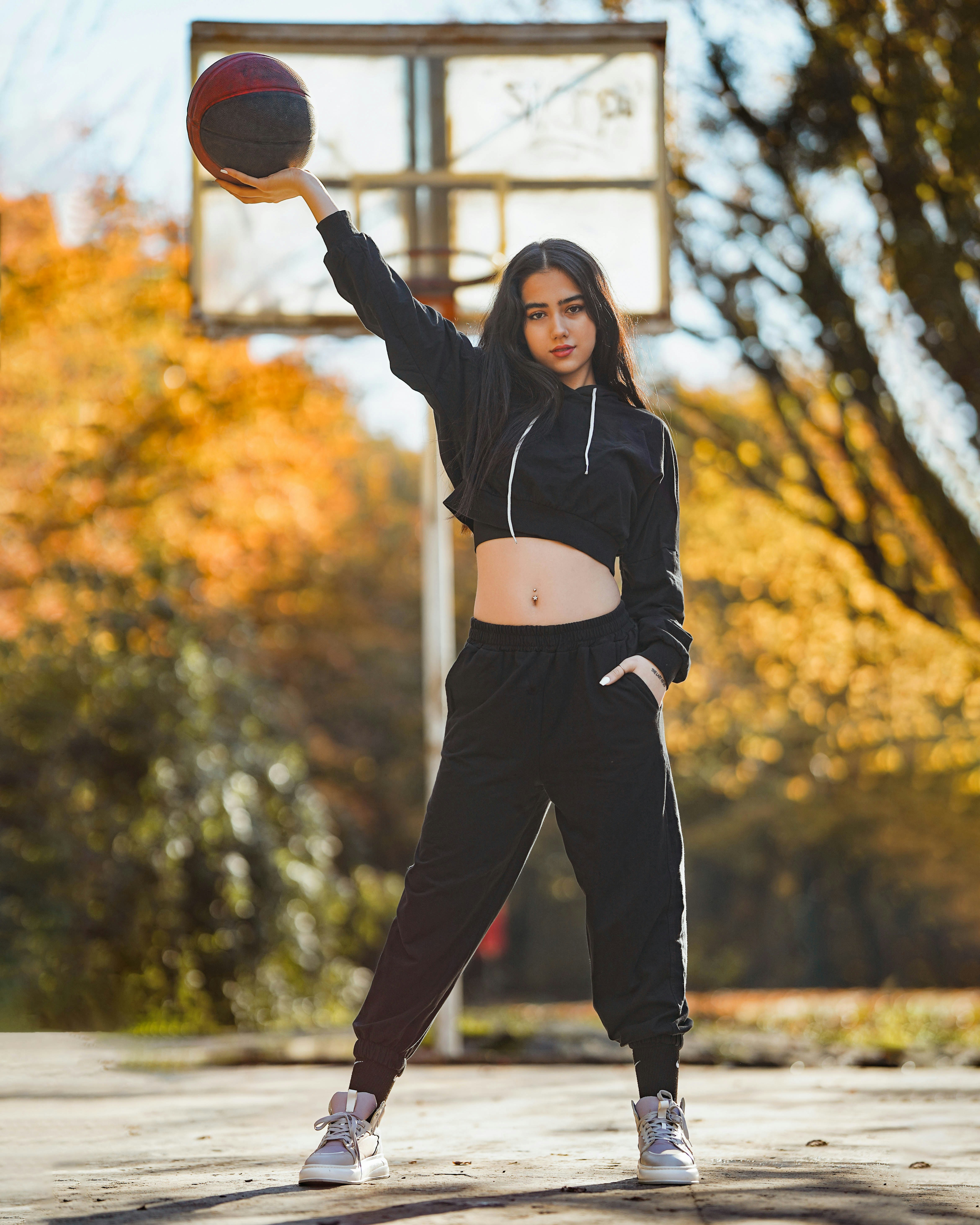 Girl poses with a basketball on the court.